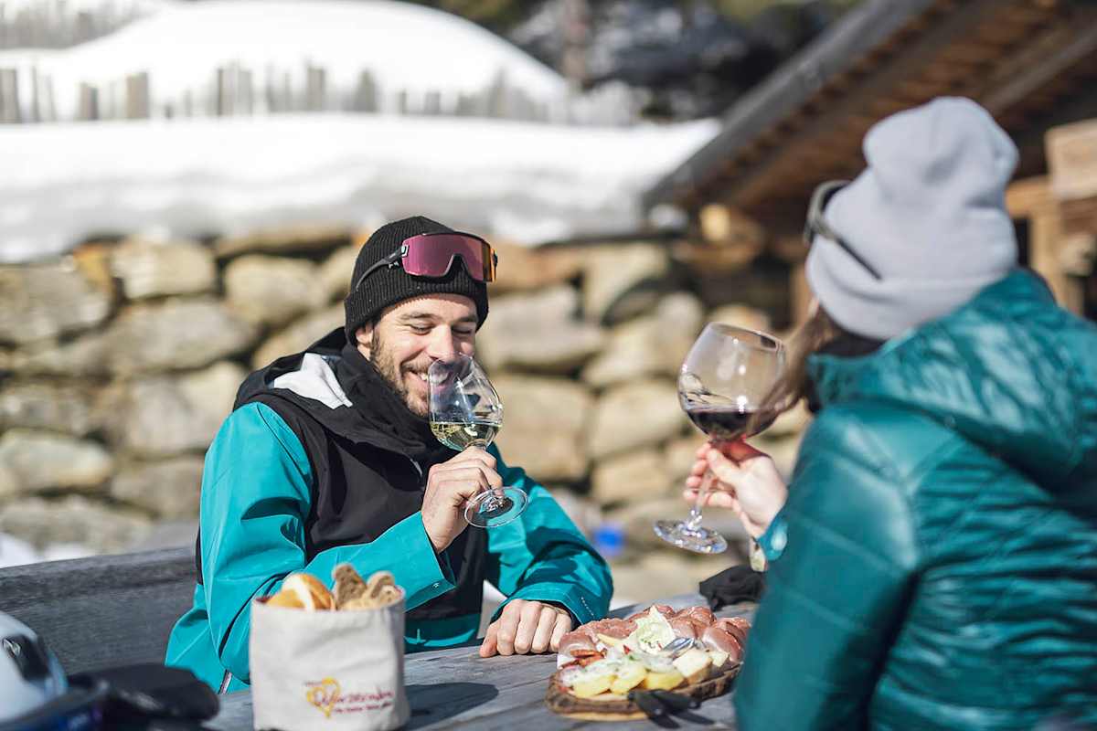 Frau und Mann beim Einkehren auf einer urigen Hütte in Ratschings mit Jause und Wein.