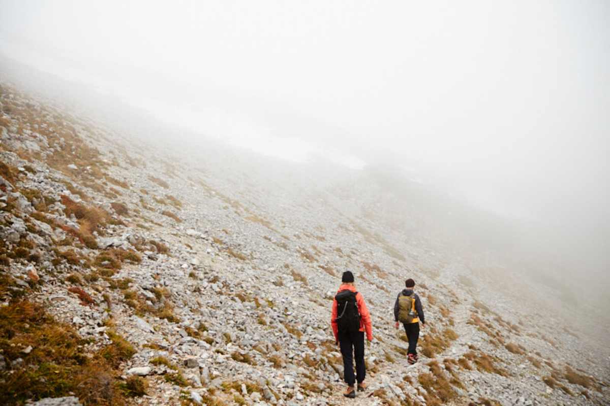 Zwei Wanderer auf der Rax auf steinigem Untergrund, Nebel erschwert die Sicht