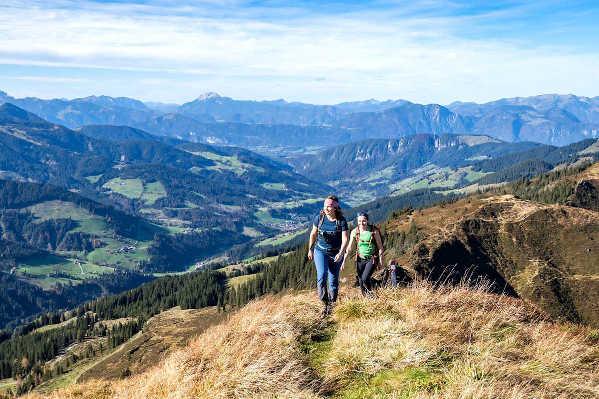 Zwei Frauen stehen auf dem Gipfel eines Berges und blicken in die Ferne.