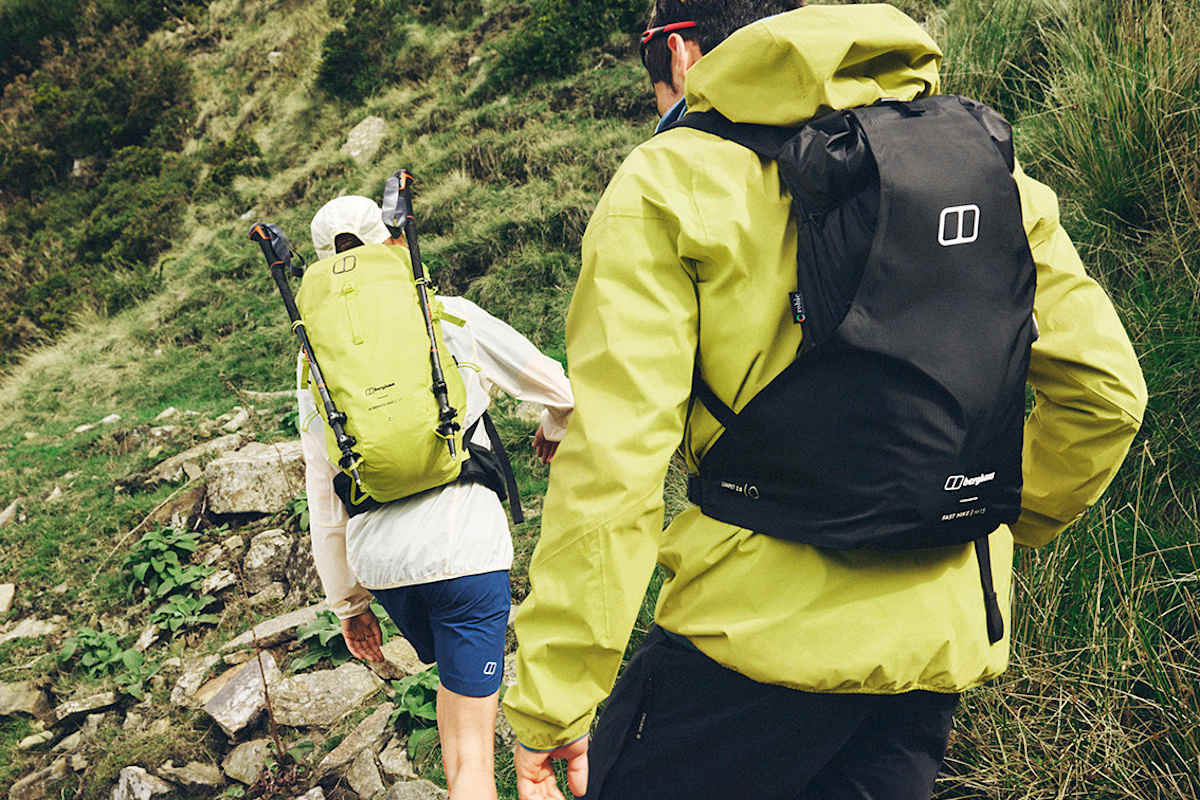 Ein Mann und eine Frau tragen Berghaus-Rucksöcke und wandern in den Bergen.