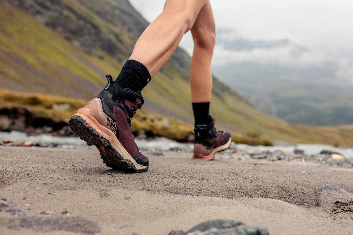 Eine Frau trägt die LOWA® EXPLORER GTX MID und geht auf unebenem Gelände.