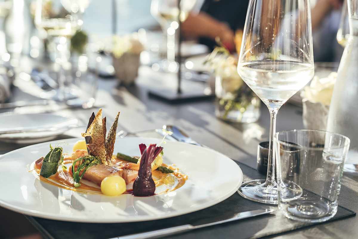 Ein Teller, auf dem Faingarniert, ein Fisch und andere regionale Zutaten zu finden sind.
