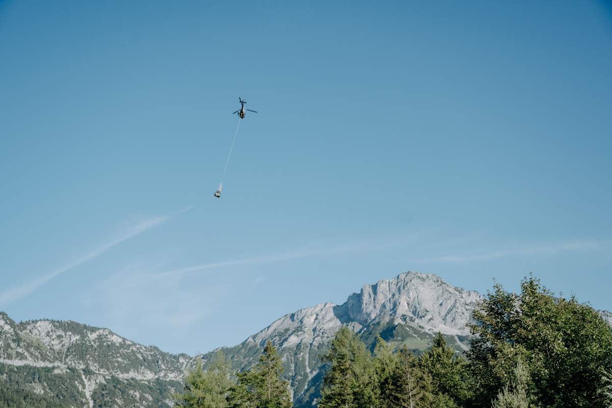 Helikopter fliegt mit Transportgut vor blauem Himmel