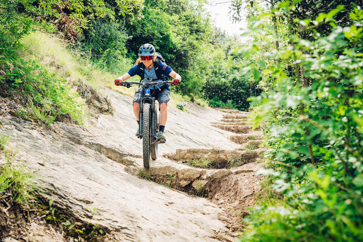 Frau fährt auf einem Mountainbike steinige Stufen bergab