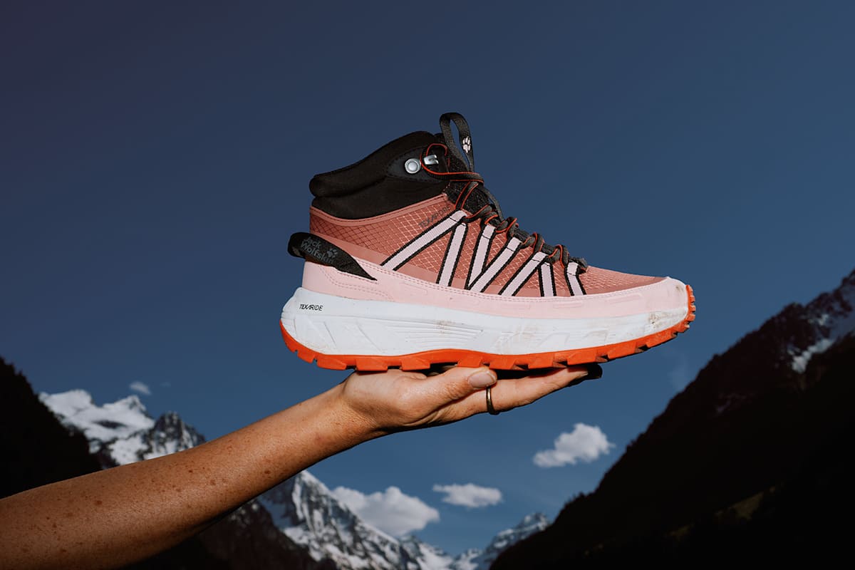 Frau hält Wild Hike Wanderschuh in Rosatönen in ihrer Hand, um ihn zu präsentieren.