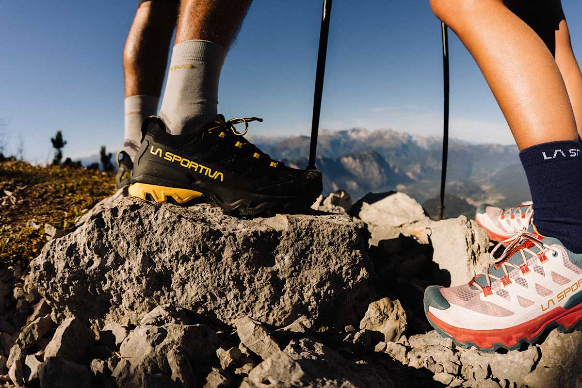 Man sieht die Füße zweier Personen, die auf einem felsigen Gipfel stehen. Sie tragen die Ultra Raptor Schuhe von La Sportiva.