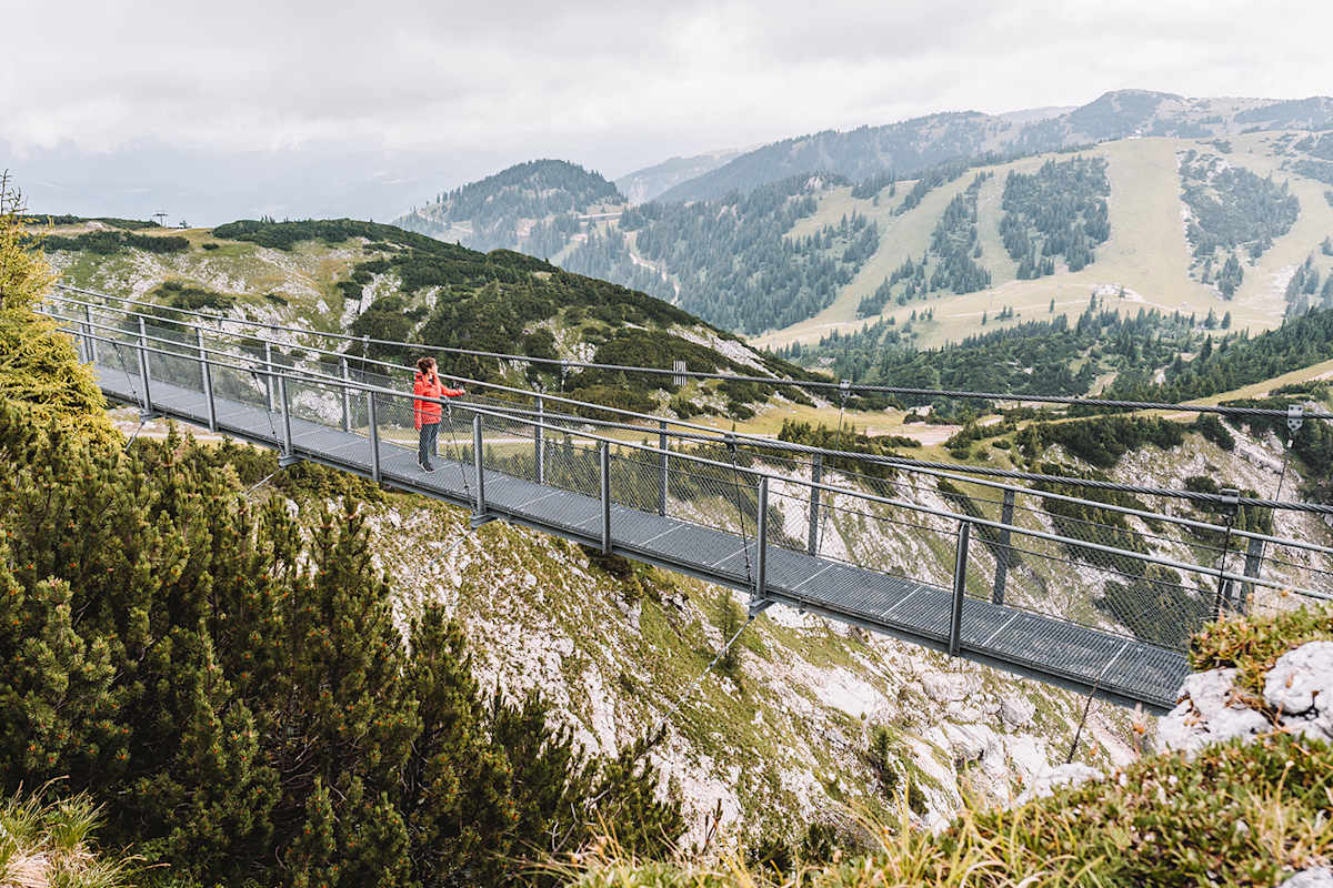 Eine Frau befindet sich auf einer Brücke am Hochkar und genießt den alpinen Ausblick.