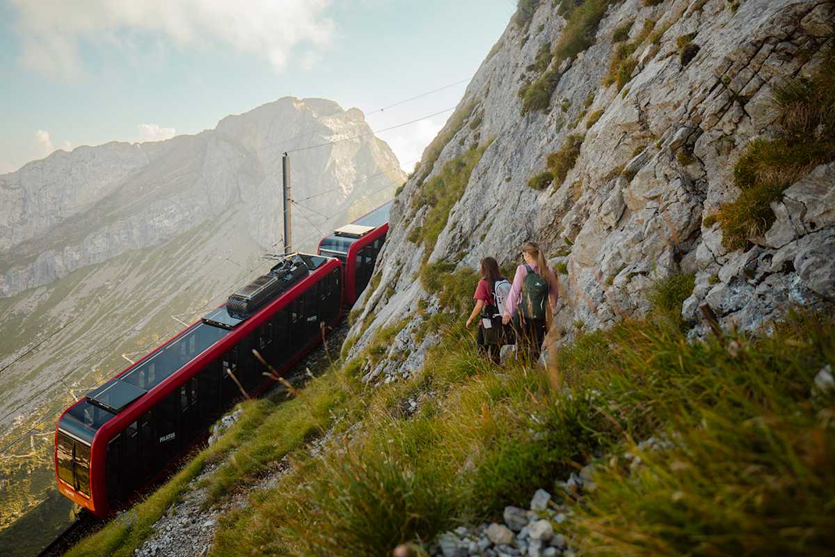 Zu sehen sind zwei felsige Gipfel und eine moderne Bahn, die nach oben an die Spitze führt.