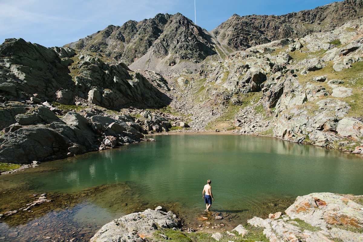 Mann watet langsam in einen Bergsee