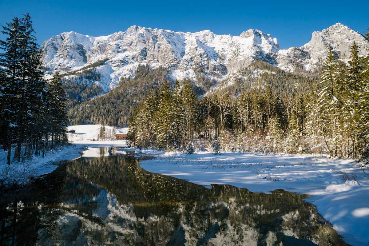 Der Hintersee bei Raumsau im Winter mit verschneiten Bergen im Hintergrund