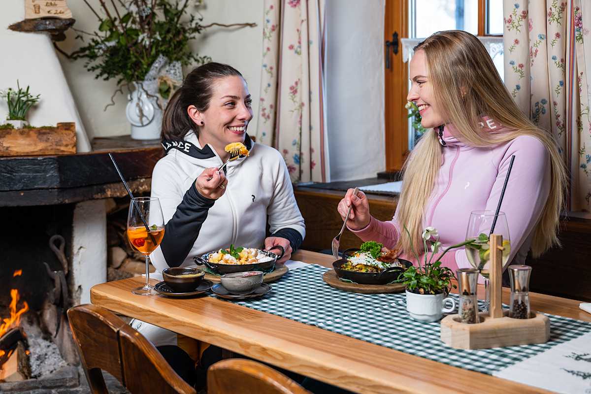 2 Frauen essen in der Hütte im Winter regionale Speisen der Skiregion Hochkönig.