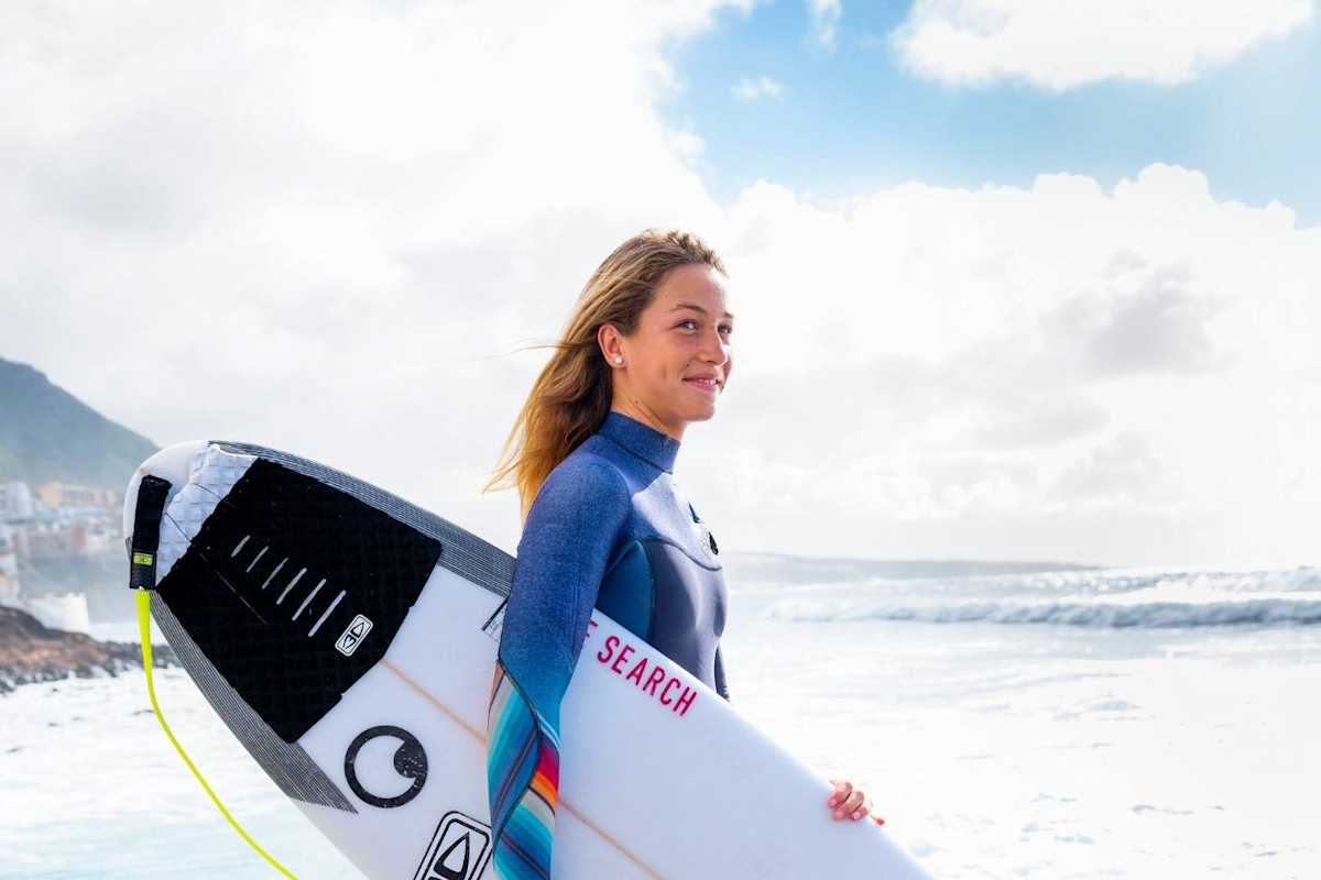 Eine Surferin mit ihren Board am Strand
