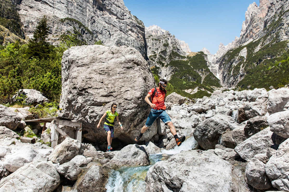 Zwei Bergwanderer beim Überqueren eines Flusses.