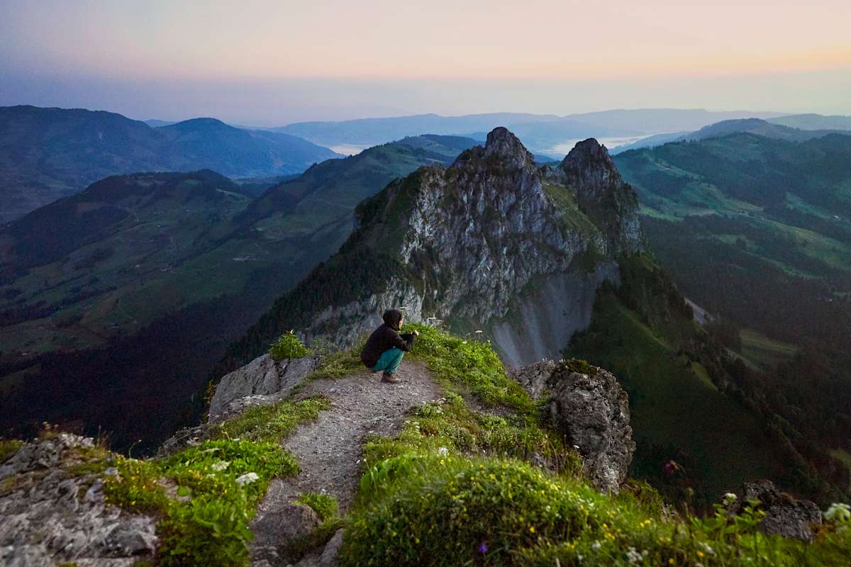 Eine Frau wartet vor wunderschönem Panorama auf den Sonnenaufgang.