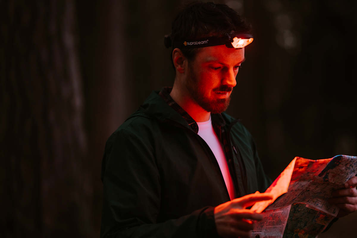 Wanderer beim Lesen einer Karte mit dem Rotlichtmodus der Suprabeam V7