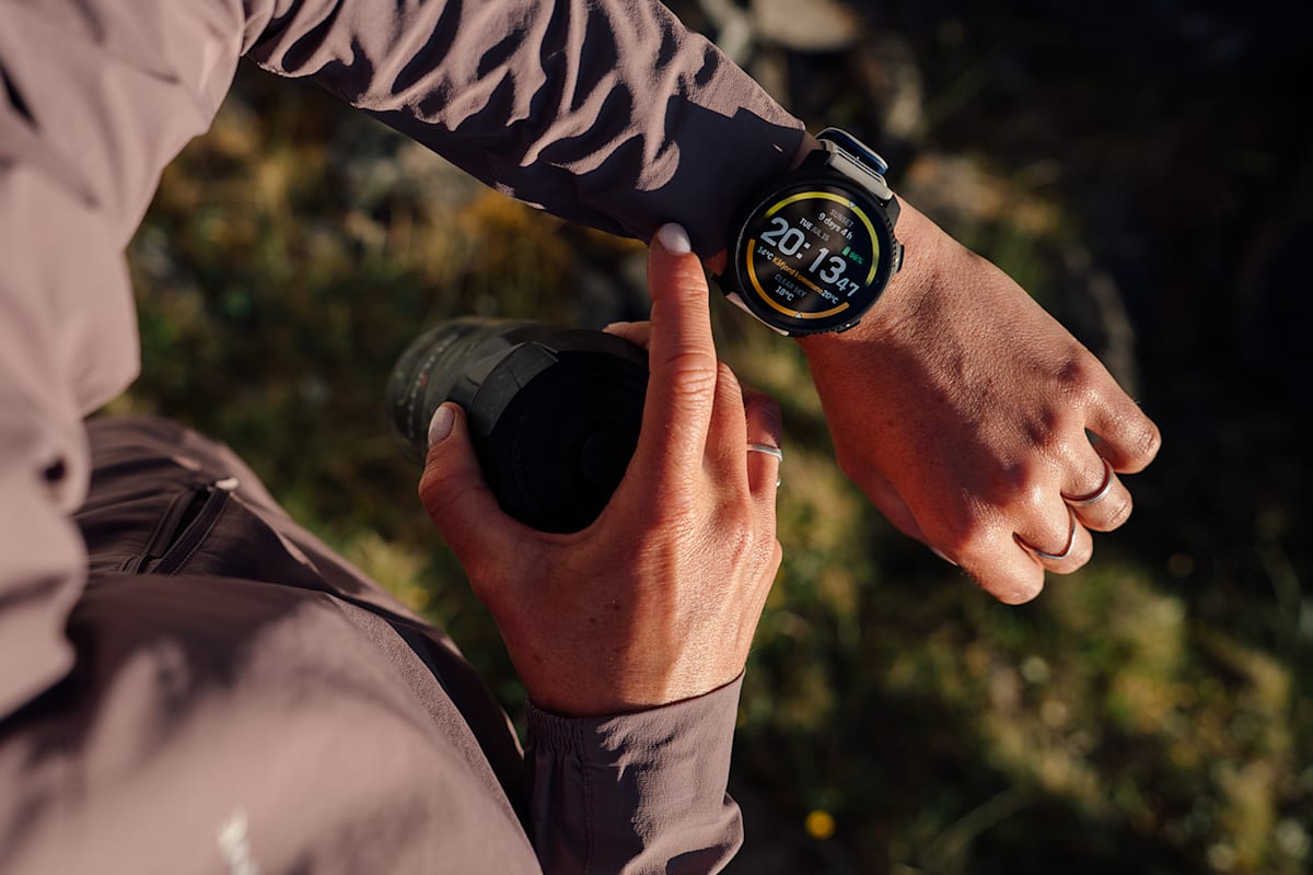 Eine Frau mit Sportkleidung schaut auf auf die Uhr auf ihrem Handgelenk von Suunto