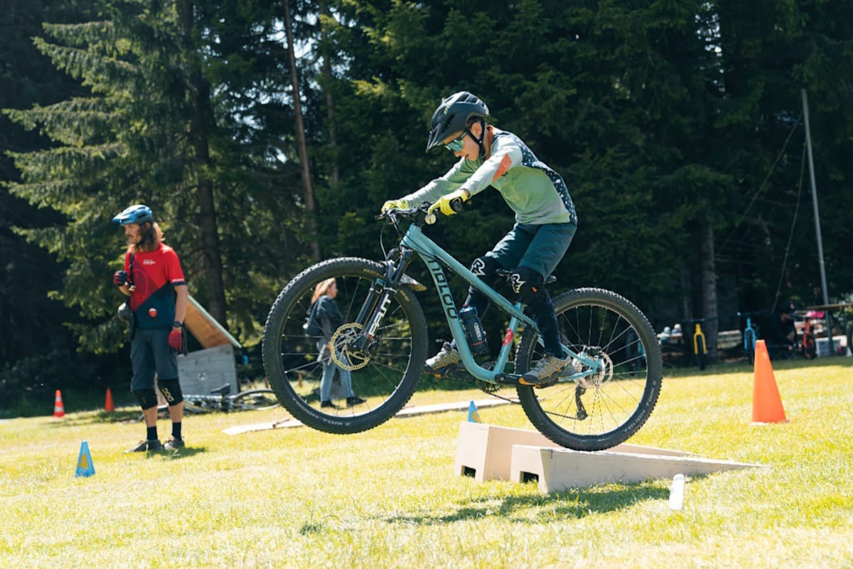 Ein Kind übt im Sommer-Rad-Kurs in der Schweiz Tricks mit dem Moutainbike.