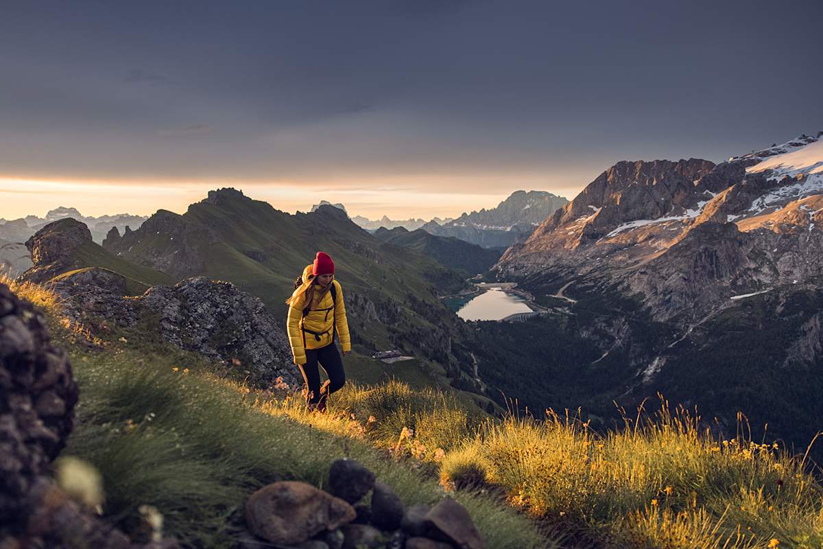 Eine Wanderin unterwegs im Val di Fassa bei Anbruch des Tages.