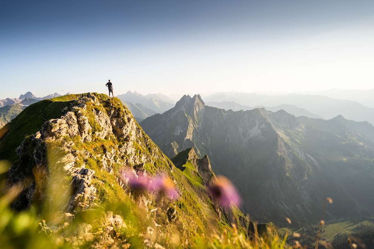 mann steht auf einem gipfel und genießt die aussicht auf die berge in oberstdorf
