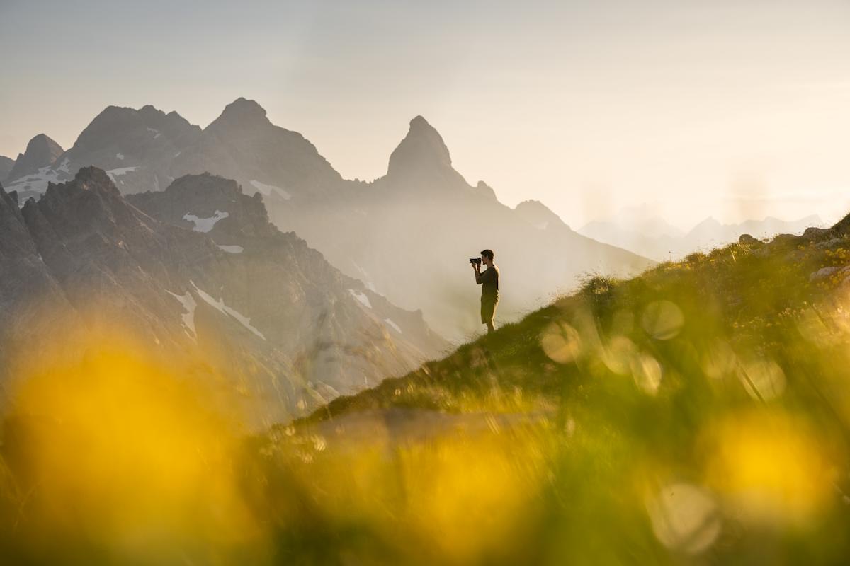 mann fotografiert auf bergspitze die landschaft in oberstdorf