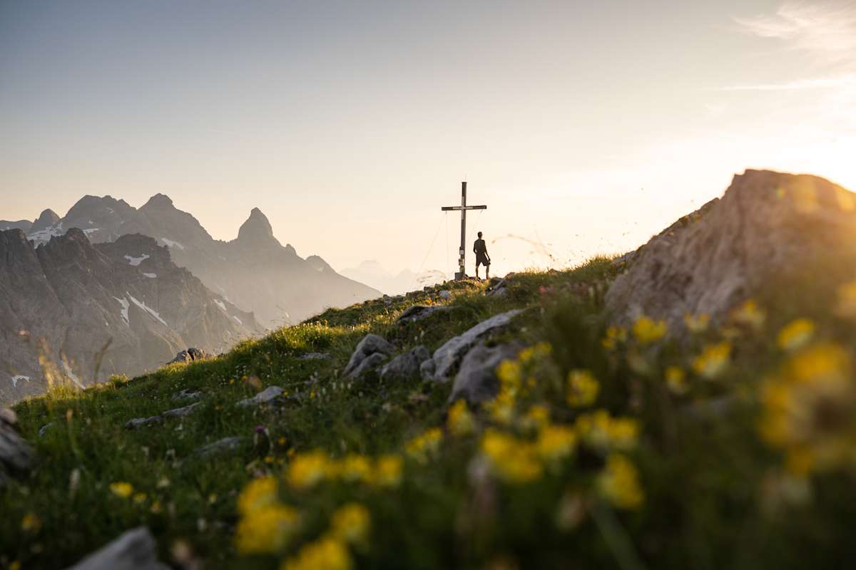 mann steht bei gipfelkreuz