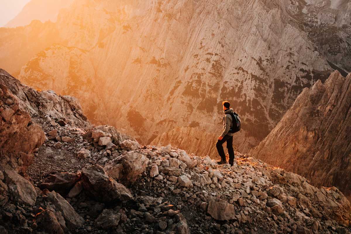Mann steht in den Dolomiten und genießt den Sonnenuntergang