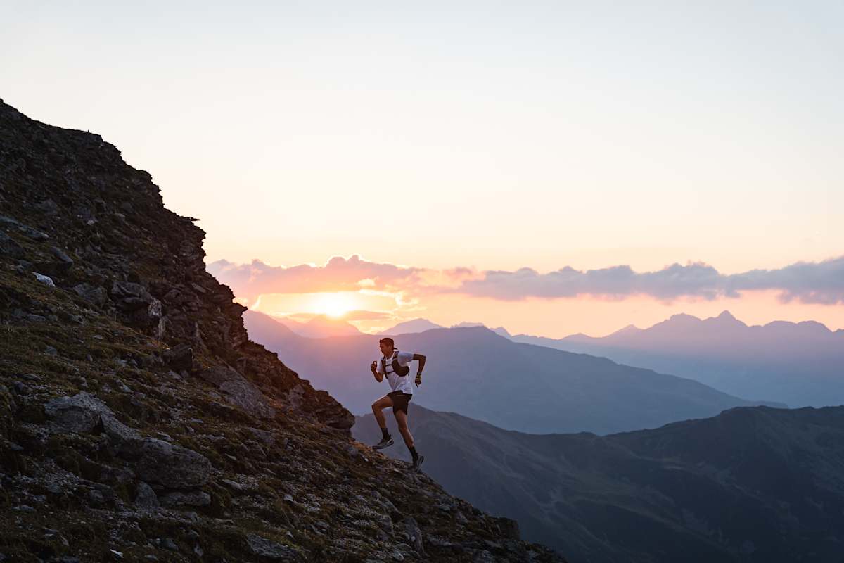 Trailrunner macht sich auf zur Bergspitze bei Sonnenuntergang