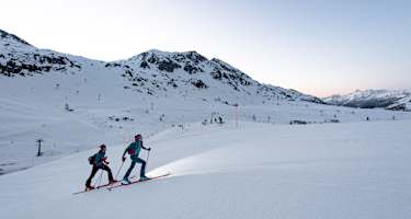 Skitourengeher auf der Skipiste am Abend