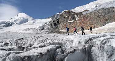 Vier Wanderer unterwegs auf einem Gletscher im Saastal.