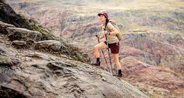 Eine Outdoor-Enthusiastin geht einen Fels hoch und trägt dabei den den LOWA® EXPLORER GTX MID Ws.