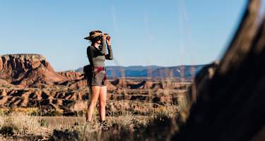 Eine Frau steht draußen in der Natur und blickt durch den CL Companion von Swarovski Optik.