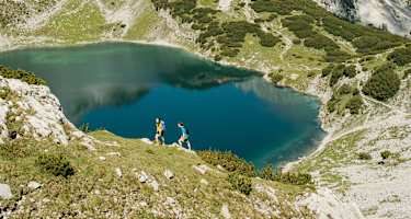 Wanderer am Drachensee in Tirol - im Hintergrund die Coburger Hütte.
