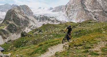 Mann fährt vor eindrucksvoller Bergkulisse mit dem Mountainbike bergab