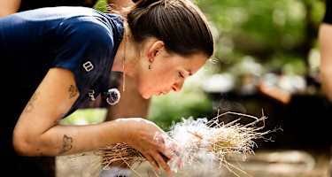 Frau macht Feuer bei Survival Camp