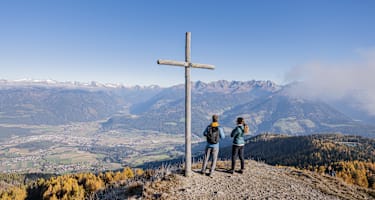 Panorama in Bruneck in Südtirol mit 2 Wanderern und einem Holzkreuz