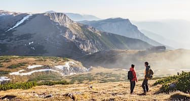 Zwei Wanderer stehen im Herbst auf dem Raxplateau und blicken in die Ferne