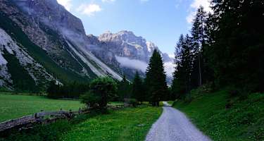 Im Flachstück des Pinnistals, kurz nach Passieren der Issenanger Alm. Die felsige Kirchdachspitze (2.840 m) im hinteren Talbereich hebt sich kontrastreich von den Bergwiesen ab. In Kürze wird der Habicht sichtbar.