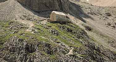 Die großartig gelegene Langkofelhütte mit dem markanten Zahnkofel darüber.