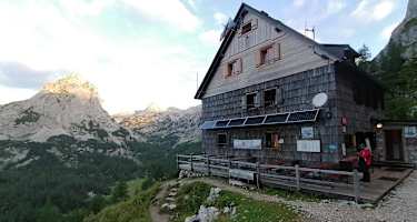 Vodnikov dom na Velem polju – dahinter das Triglav-Massiv und Mišelj vrh (li)