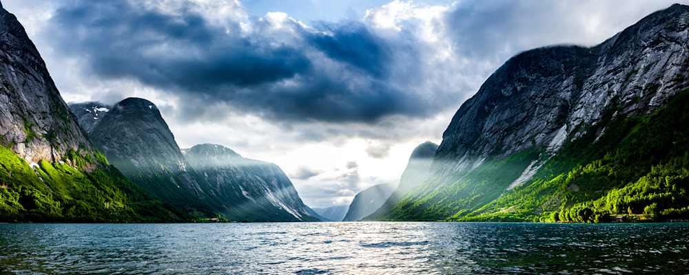 Norwegischer Fjord bei Sonnenaufgang mit schroffen Klippen und Wald