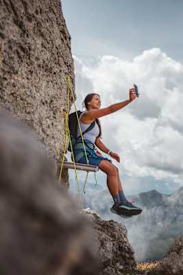 Klettersteig Dolomiten, Eggental: Frau auf Hängebank im Klettersteig, die mit dem Handy ein Selfie macht