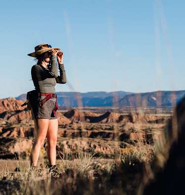 Eine Frau steht draußen in der Natur und blickt durch den CL Companion von Swarovski Optik.