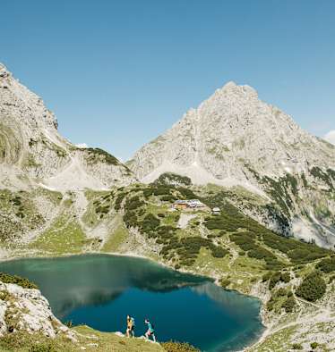 Wanderer am Drachensee in Tirol - im Hintergrund die Coburger Hütte.
