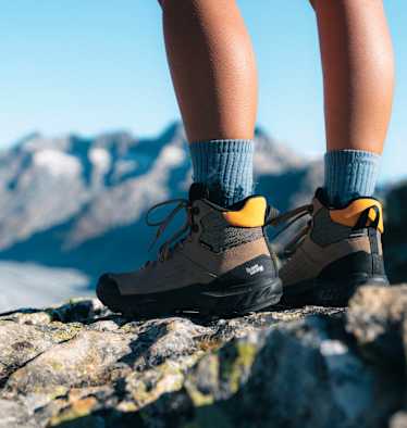 Beine von Wanderern in robusten Bergschuhen von Hanwag – im Hintergrund Berge und Gletscher