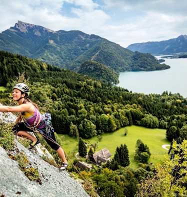 Manuela klettert am Plombergstein, im Hintergrund der türkise Wolfgangsee