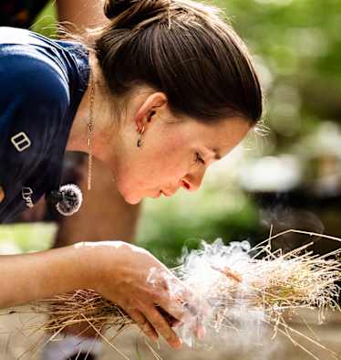 Frau macht Feuer bei Survival Camp