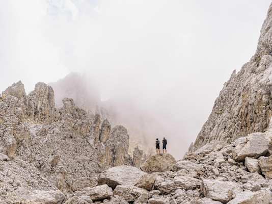 Zwei Wanderer inmitten bizarrer Felsformationen und ein wenig Nebel im Latemarmassiv.