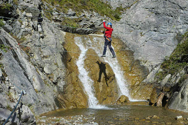 Kletterer balanciert auf einem Seil über einen Bach im Klettersteig Millnatzenklamm