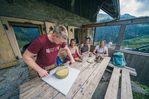 Auf einer Alm an der Milchstraße am Karnischen Höhenweg wird ein Käse frisch angeschnitten.
