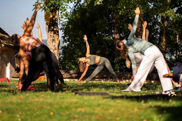 Eine Gruppe an Menschen macht Yoga in der Wiese